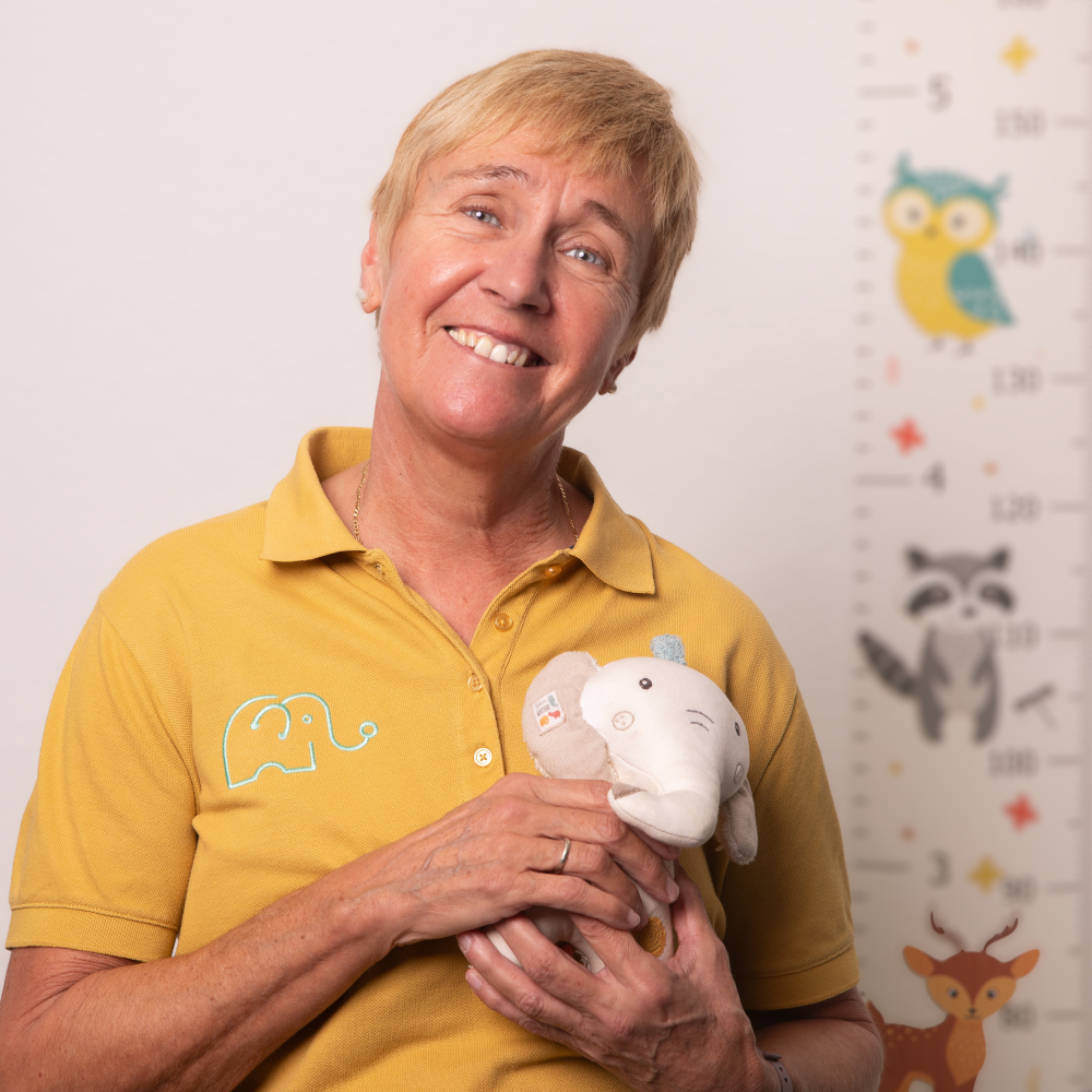 Personalbild der Mitarbeiterin Dagmar Kirschey, die das Praxismaskottchen, einen kleinen Spielzeugelefanten, hochhält.